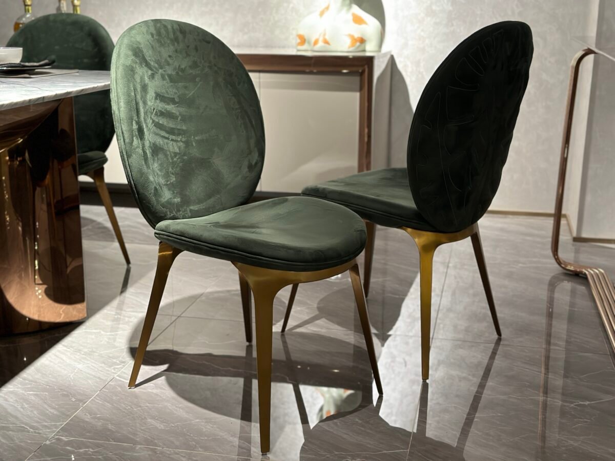 Luxury upholstered dining chair brushed gold metal detail green leather upholstery close-up