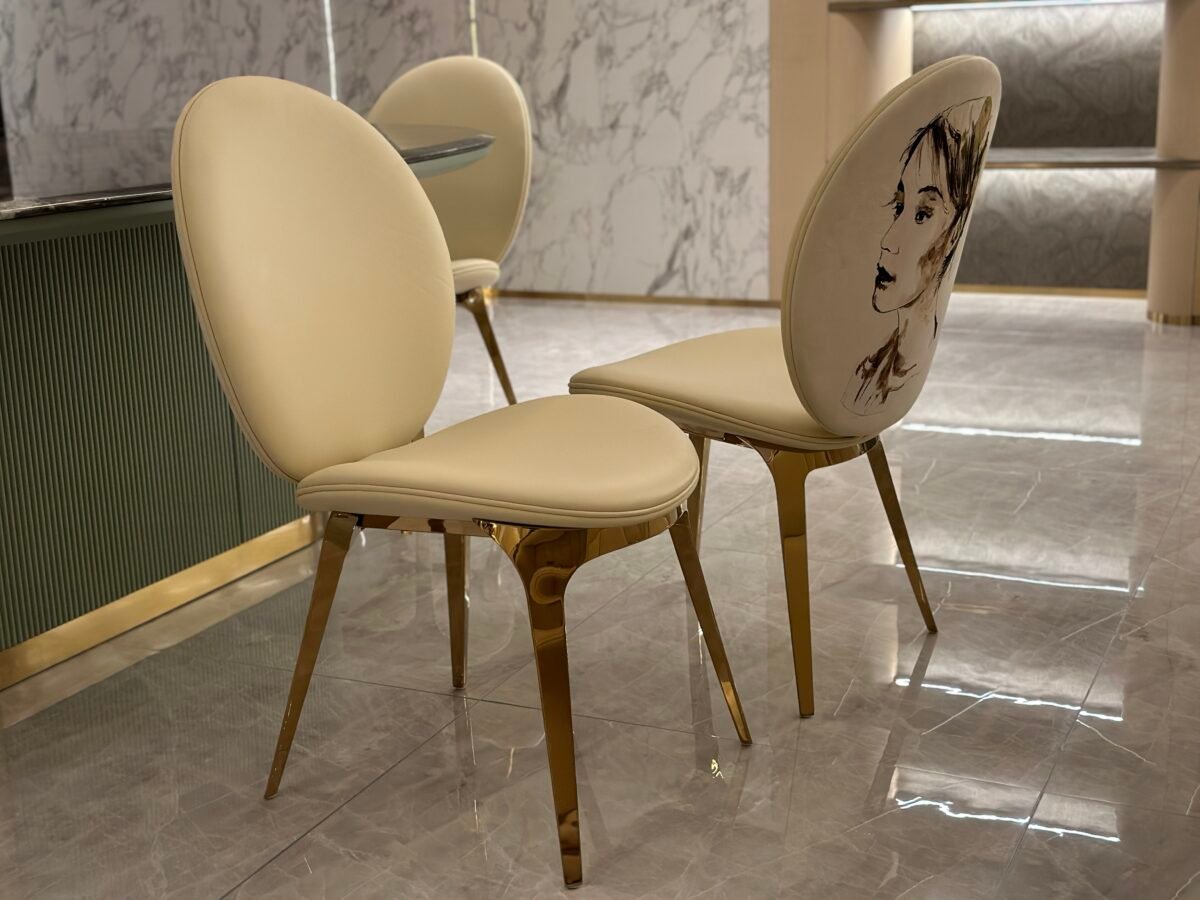 Luxury upholstered dining chair brushed gold metal detail white leather upholstery close-up
