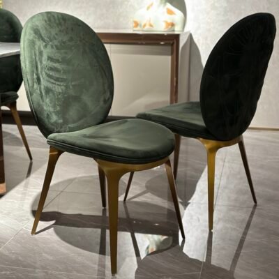 Luxury upholstered dining chair brushed gold metal detail green leather upholstery close-up