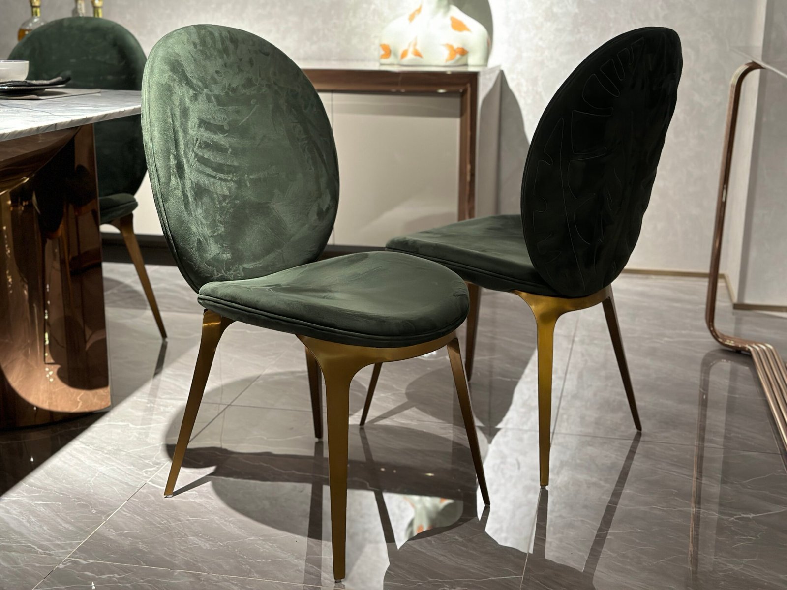 Luxury upholstered dining chair brushed gold metal detail green leather upholstery close-up