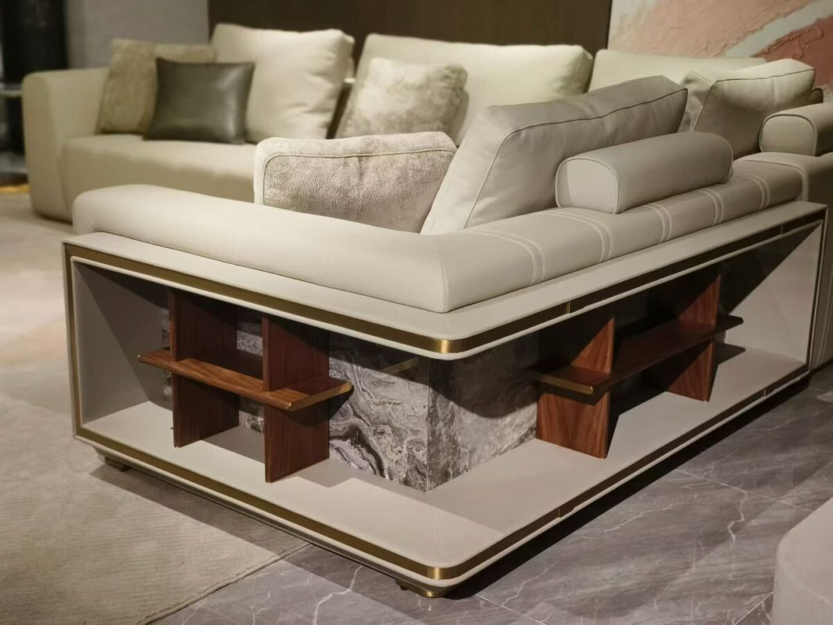 Close-up brushed gold frame and Venetian brown stone slab detail on white leather sectional